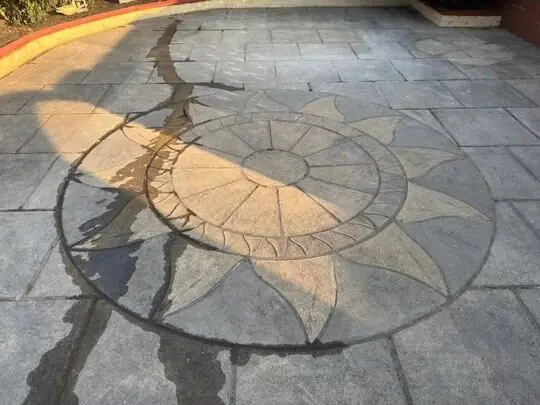 Patio with a sunburst pattern before cleaning, dark with algae